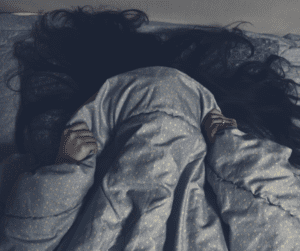 Picture of a girl hiding in her bed under the sheets